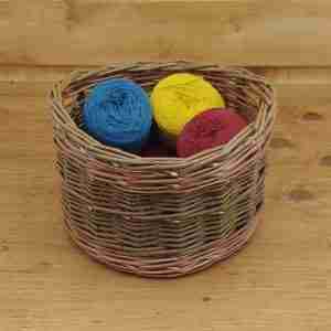 Olive green willow round storage basket with two buff coloured bands and handles under the rim, inside are bright wool balls
