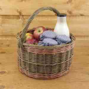 Round willow shopping basket with milk, apples and jam inside